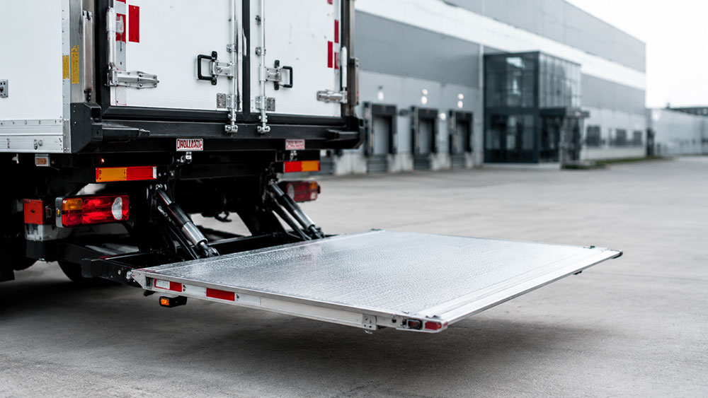 Hydraulic tail lift platform extended on a commercial freight truck at a logistics warehouse
