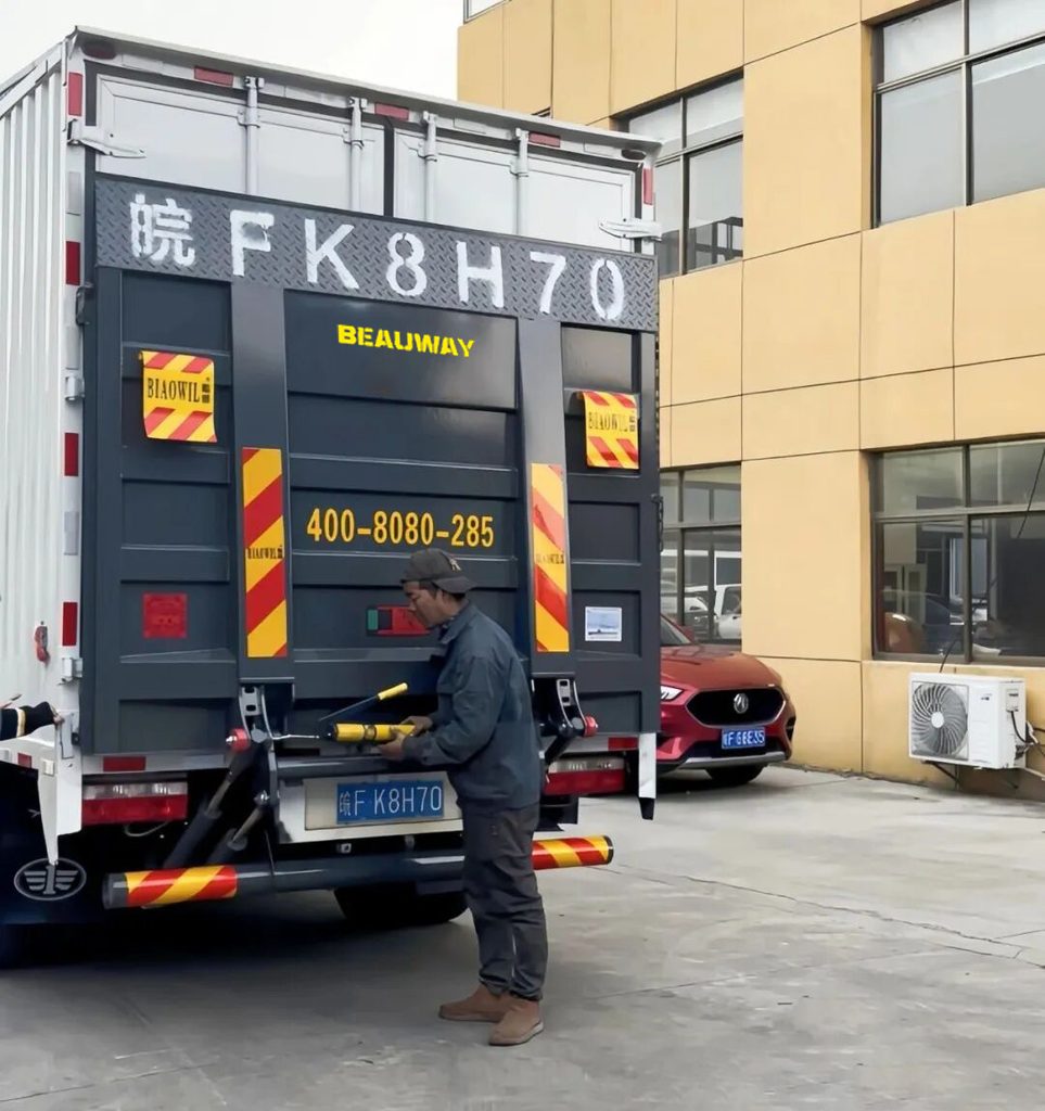 Technician applying grease during tail lift pin lubrication maintenance